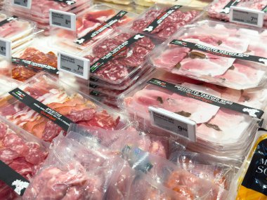 Villach, Avusturya - 21 Ağustos 2025: Karışık meze etleri bir markette güzelce düzenleniyor, açık pakette prosciutto ve salam vurgulanıyor