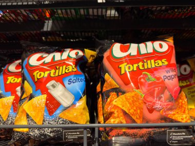 Villach, Avusturya - 21 Ağustos 2025: Chio Tortillas atıştırmalık poşetleri, renkli ambalajlı tuzlu ve yabani kırmızı biber aromalı bir markette sergileniyor