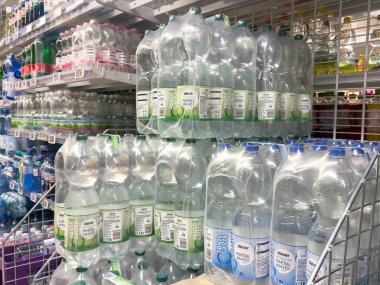 Villach, Avusturya - 21 Ağustos 2025: Bakkal raflarında su şişeleri düzenli olarak düzenlenmekte olup, tüketiciler için farklı marka ve ambalaj şekilleri gösterilmektedir