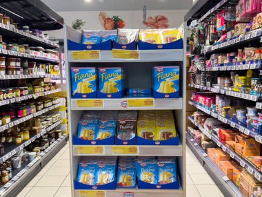 Villach, Avusturya - 21 Ağustos 2025: Turta ve puding tatlıları süpermarket raflarında renklendirici ambalajlar ve cazip sunumlar eşliğinde düzgünce düzenlenmiştir