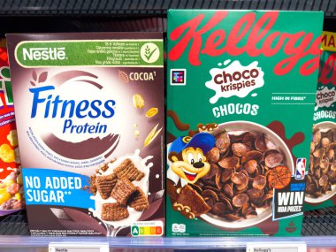 Villach, Avusturya - 21 Ağustos 2025: Nestle Fitness Protein ve Kellogg 's Choco Krispies mısır gevreği kutuları belirgin bir şekilde renkli tasarımları ön plana çıkaran bir süpermarket rafında sergilenmektedir