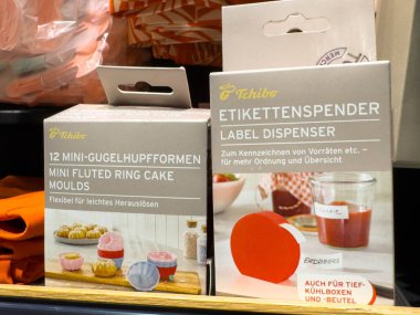 Villach, Avusturya - 21 Ağustos 2025: Tchibo 'nun mini flütlü kek kalıpları ve etiket makinesi renkli bir mutfak ortamında güzelce düzenlenmiştir.