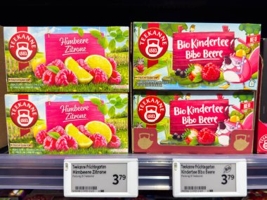 Villach, Avusturya - 21 Ağustos 2025: Ahududu limonlu Teekanne meyve çay kutuları ve süpermarket raflarında sergilenen Bibo Berry aromalı renkli ambalajlar