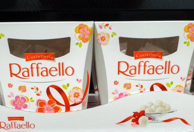 Villach, Avusturya - 21 Ağustos 2025 Raffaello şeker kutuları raflarda güzelce düzenlenmiştir, çiçek desenleri ve tatlı aşıkları için cazip hindistan cevizi ikramları sunulmaktadır.