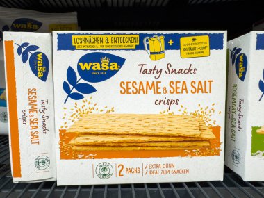 Villach, Avusturya - 21 Ağustos 2025: Wasa susamı ve deniz tuzu cipsi ambalajı süpermarket rafında belirgin bir şekilde sergilenmekte, lezzetli atıştırmalık seçenekleri vurguluyor