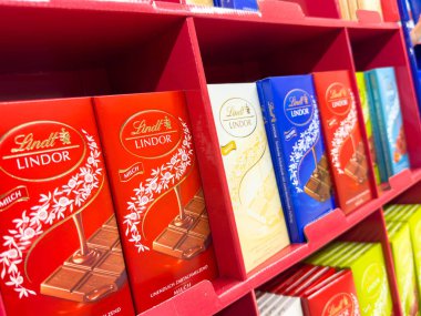 Villach, Avusturya - 21 Ağustos 2025: Lindt Lindor çikolataları, çeşitli tatları ve renkli ambalajları perakende seti içinde vurguluyor