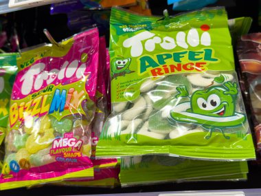 Villach, Avusturya - 21 Ağustos 2025: Ekşi vızıltı karışımı ve elma halkaları içeren parlak renkli Trolli şeker torbaları, canlı bir perakende satış ortamında sergilendi