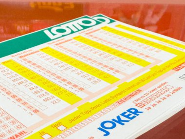 Villach, Avusturya - 21 Ağustos 2025: Piyango bileti, piyango oyunlarının heyecanını temsil eden parlak kırmızı bir arkaplan karşısında seçilmiş sayılar ve seçenekler sunuyor