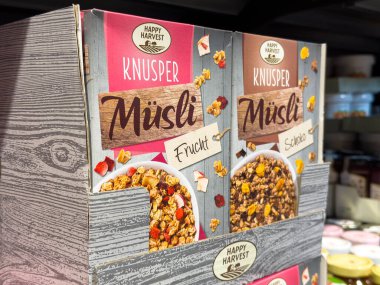 Villach, Avusturya - 21 Ağustos 2025: Mutlu Hasat Knusper Musli mısır gevreği kutuları, renkli ambalajlarda meyve ve çikolata aromaları vurgulanarak bir market rafına yerleştirildi
