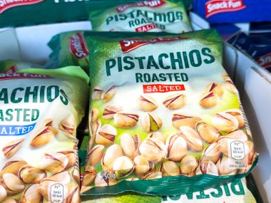 Villach, Avusturya - 21 Ağustos 2025: Atıştırmalık kavrulmuş, yeşil ambalajlı şam fıstıkları, sağlıklı atıştırmalıklar için lezzetli tuzlu fındıkları ön plana çıkaran bir mağaza rafına yerleştirilmiştir.