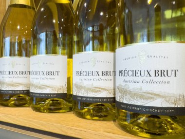 Villach, Avusturya - 21 Ağustos 2025: Şişe Precieux Brut köpüklü şarap ahşap bir rafta sergileniyor, zarif etiketi ve kaliteli kalitesi vurgulanıyor