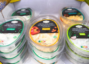 Villach, Avusturya - 21 Ağustos 2025: Taze peynirin rengarenk konteynerleri düzgünce düzenlenerek, bir bakkal ortamında farklı aromalar vurgulanıyor