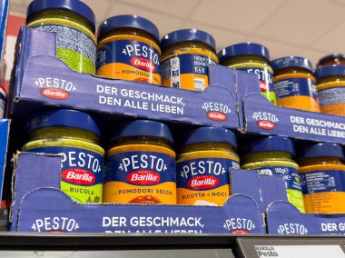 Villach, Avusturya - 21 Ağustos 2025: Barilla pesto kavanozları zengin renkler ve aşçılık meraklıları için cazip etiketler içeren bir süpermarket rafında tertiplenmiştir.
