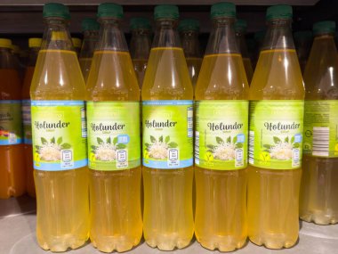 Villach, Avusturya - 21 Ağustos 2025: Bir süpermarket rafında renkli etiketler ve canlandırıcı içecek seçenekleri vurgulanarak Holunder Elderflower içecekleri sergileniyor