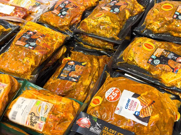 Villach, Avusturya - 21 Ağustos 2025: Markette çeşitli marine edilmiş et paketleri, yemek pişirme ilhamı için zengin renkleri ve tatları vurguluyor