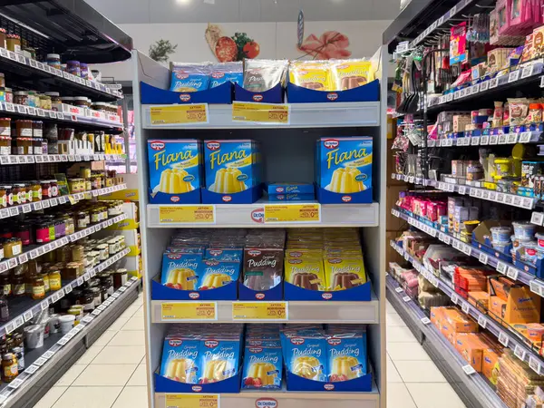 Villach, Avusturya - 21 Ağustos 2025: Turta ve puding tatlıları süpermarket raflarında renklendirici ambalajlar ve cazip sunumlar eşliğinde düzgünce düzenlenmiştir