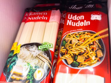Villach, Avusturya - 24 Ağustos 2025: Ramen ve Udon erişte paketleri sebze etiketleri ve yemek meraklıları için renkli tasarımlar ön plana çıkarılarak bir rafa dizildi