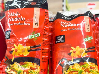 Villach, Avusturya - 24 Ağustos 2025: Wok erişte ambalajı belirgin bir şekilde bir süpermarket rafında sergileniyor, canlı renkler ve vegan etiketi vurgulanıyor