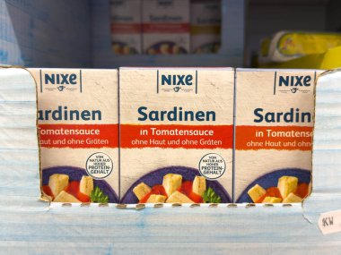 Avusturya 'nın Villach kenti - 24 Ağustos 2025: Domates soslu nixe sardalyalar, çekici ambalaj ve renkleri vurgulayan bir süpermarket rafında düzgünce düzenlenmiştir.