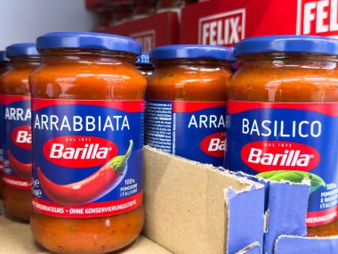 Villach, Avusturya - 24 Ağustos 2025: Arrabbiata ve Basilico aromalı Barilla makarna sosu kavanozları canlı ambalajlarını ön plana çıkaran bir markette sergileniyor