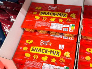 Villach, Avusturya - 24 Ağustos 2025: Bir mağazada gösterilen abur cubur günü karışık ambalajı, canlı renkler ve sosyal toplantılar için çeşitli atıştırma şekilleri vurgulanıyor