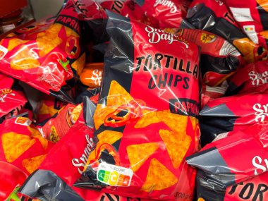 Villach, Avusturya - 24 Ağustos 2025: Paprika aromalı parlak renkli tortilla paketleri bir bakkal rafında düzenlenerek, davetkar bir aperatif sergisi oluşturuldu