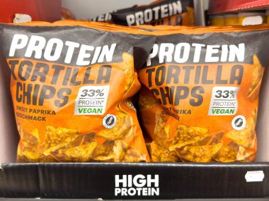 Villach, Avusturya - 24 Ağustos 2025: Protein paketlenmiş tortilla cipsleri göz alıcı paketlerde tatlı kırmızı biber aromalı, vegan seçenekler arayan sağlıklı beslenmeyi seven aşıklar için ideal