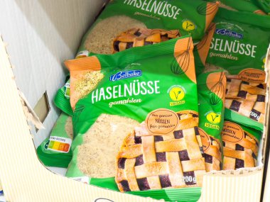 Villach, Avusturya - 24 Ağustos 2025: Renkli ambalajlarda yer fındıkları bir bakkalda, tazeliklerinin ve kalitelerinin altını çizerek düzgünce düzenlenmiştir