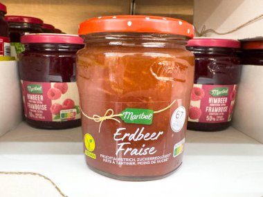 Villach, Avusturya - 24 Ağustos 2025: Maribee Erdbeer çilek reçel kavanozu ahududu reçelleri ile bariz bir şekilde rafa konur, çekici tasarımı ve tadı vurgulanır