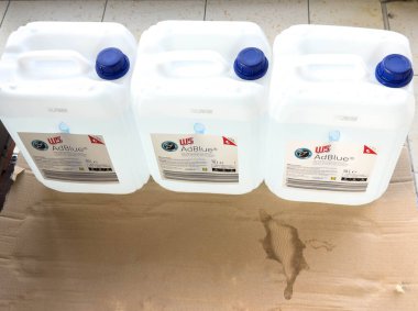 Villach, Avusturya - 24 Ağustos 2025: Otomotiv uygulamaları için markalaşma ve paketleme detaylarını vurgulayan üç AdBlue konteynırı karton üzerinde konumlandırılmıştır