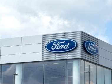 Udine, İtalya - 26 Ağustos 2025: Ford bayii ön cephesinde parlak gökyüzü ile parlak modern bina tasarımına karşı tanınabilir mavi oval logo sergileniyor