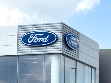 Udine, İtalya - 26 Ağustos 2025: Pürüzsüz tasarım ve parlak mavi gökyüzü altında geniş logo içeren Ford bayiliğinin dış görünümü, marka varlığı ve modernliği vurguluyor