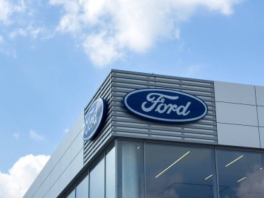 Udine, İtalya - 26 Ağustos 2025: Ford bayiliği, modern bina dış yüzeyinde müşterileri otomotiv sunumları ve hizmetlerini keşfetmeye davet eden belirgin mavi bir logoya sahiptir.