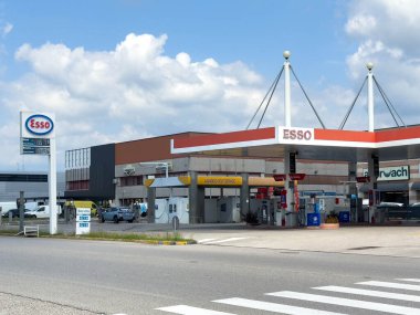 Udine, İtalya - 26 Ağustos 2025: Esso benzin istasyonu, hareketli bir karayolu üzerinde yer alan akaryakıt pompaları ve bakkal ile çağdaş tasarımı içeriyor