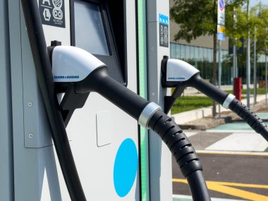 Udine, İtalya - 26 Ağustos 2025: Elektrikli araç şarj istasyonu, sürdürülebilir enerji teknolojisindeki gelişmeleri vurgulayarak, şehir merkezlerinde ikili bağlantılara sahip.