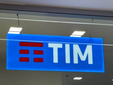 Udine, İtalya - 26 Ağustos 2025: TIM logosu, modern markalaşma ve telekomünikasyon odaklarını vurgulayarak, parlak mavi arkaplanlı bir perakende ortamda sergilenmektedir