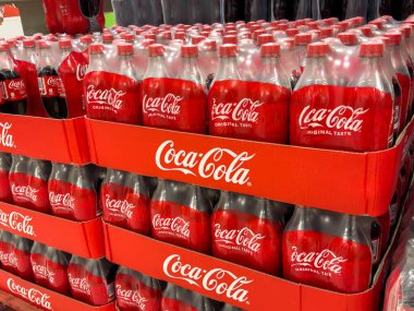 Udine, İtalya - 26 Ağustos 2025: Coca-Cola şişeleri, markanın ikonik kırmızı rengini ve orjinal tat ve fotokopi alanının altını çizerek renkli bir şekilde sergilenmektedir.