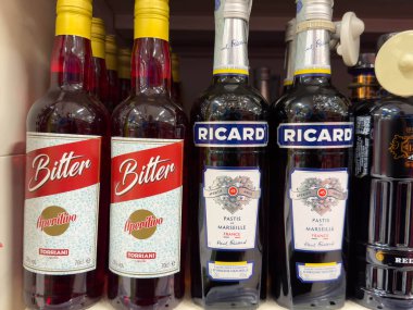 Udine, İtalya - 26 Ağustos 2025: Bitter ve Ricard Pastis şişeleri bir rafa dizilmiş, bir perakende seti içinde eşsiz tasarımları ve renkleri vurgulanıyor