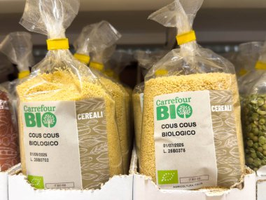 Udine, İtalya - 26 Ağustos 2025: Carrefour BIO kuskus torbaları süpermarket raflarında organik malzemelerin altını çizerek ve çekici tasarım yaparak düzenli bir şekilde düzenlenmiştir