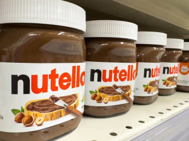 Udine, İtalya - 26 Ağustos 2025: Süpermarket raflarında sergilenen Nutella kavanozları, çekici markalar ve dokularla yayılmış ünlü çikolata fındığı vurguluyor
