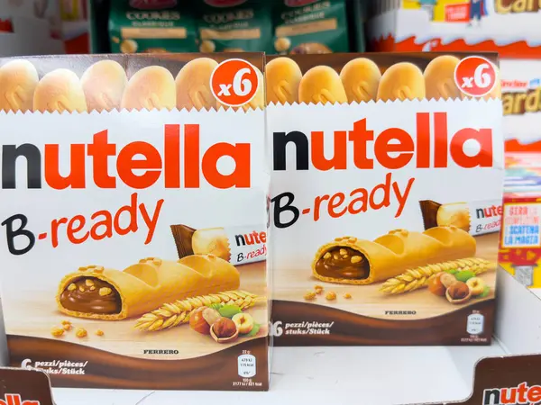 Udine, İtalya - 26 Ağustos 2025: Nutella B-hazır abur cubur kutuları bir süpermarket rafına yerleştiriliyor, lezzetli çikolata dolu pastalar ve canlı markalar vurgulanıyor