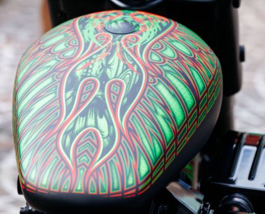 Villach, Avusturya - 05 Eylül 2025: Özel Harley Davidson yakıt tankı, Avrupa Bisiklet Haftası 'nda işçiliğin altını çizerek, karmaşık yeşil ve kırmızı kabile sanat eserleri sergiliyor