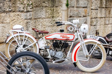 Villach, Avusturya - 05 Eylül 2025: Vintage Harley Davidson motosikleti Avrupa Bisiklet Haftası boyunca dokuma taştan bir duvara sergilenerek klasik tasarımını ön plana çıkardı