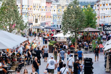 Villach, Avusturya - 05 Eylül 2025: Kalabalık sokak manzarası açık kafelerde yemek yiyen insanlar, renkli dekorasyonlar ve hareketli ambiyanslarla çevrili