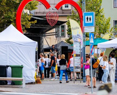 Villach, Avusturya - 05 Eylül 2025: Açık hava festivali sahnesi, canlı müzik ve yemek tezgahlarından keyif alan insanların yer aldığı kalp şeklinde bir kemer sergiliyor