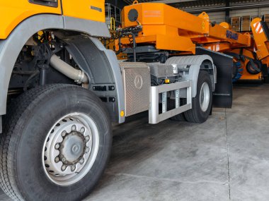 Klagenfurt, Avusturya - 25 Eylül 2025: Ağır yük kamyonu endüstriyel garaj ortamında ayrıntılı tekerlek ve makine parçaları barındırıyor