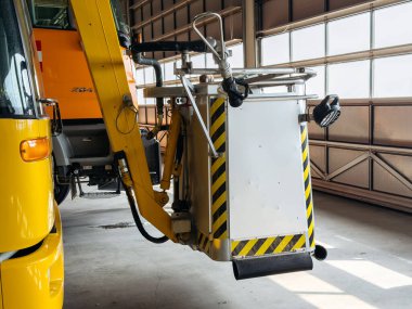 Klagenfurt, Avusturya - 25 Eylül 2025: Endüstriyel ambiyansı olan geniş bir hangara yerleştirilmiş, pist onarımı için özel aletlerle donatılmış sarı bakım aracı