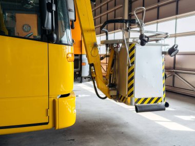 Klagenfurt, Avusturya - 25 Eylül 2025: Sarı havaalanı bakım aracı hangarda park etmiş hidrolik asansör, endüstriyel tasarım ve operasyonel verimliliği vurguluyor