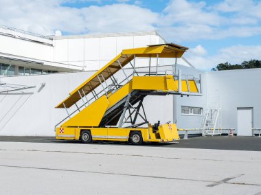 Klagenfurt, Avusturya - 25 Eylül 2025: Terminal tarafından yerleştirilmiş sarı merdiven aracı, havaalanı operasyonlarındaki yapısını ve amacını vurguluyor
