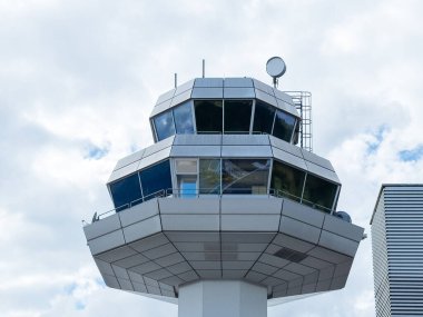 Klagenfurt, Avusturya - 25 Eylül 2025: Modern havaalanı kontrol kulesi panoramik pencereler, canlı bir havaalanı ayarında hava trafiği ve uçuş operasyonlarını denetliyor